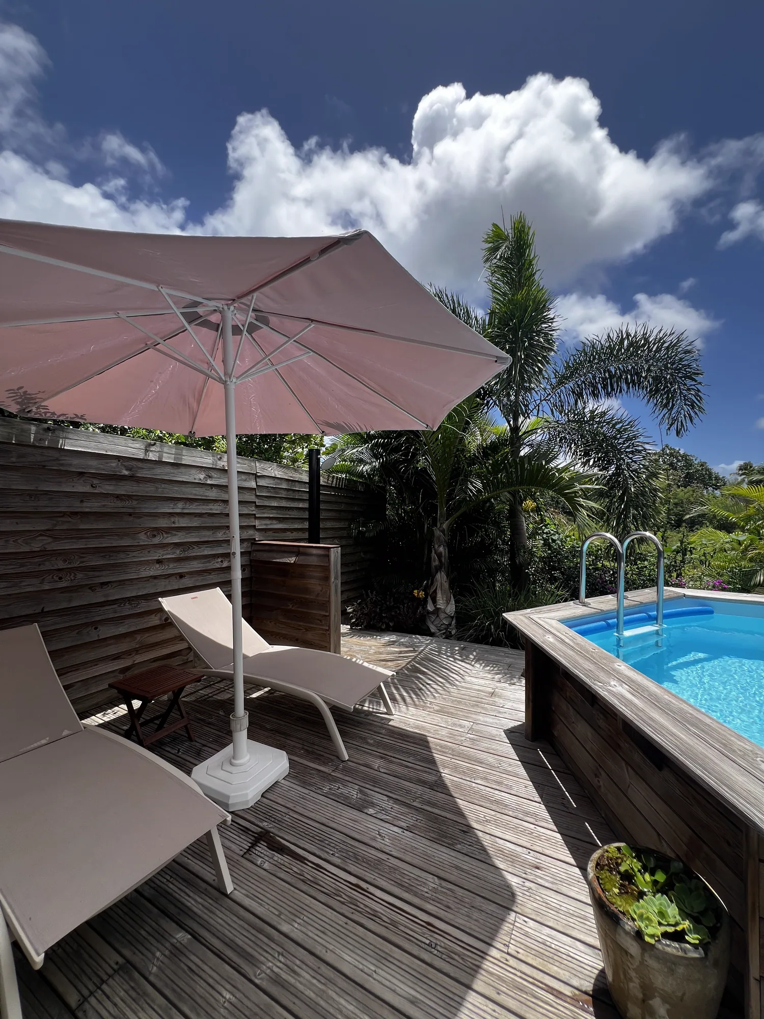 Terrasse en bois avec transats et parasol au bord de la piscine